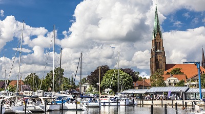 Schleswigs domkyrka i brunt tegel och orange tegeltak, i f�rgrunden stadens hamn med fr�mst segelb�tar.